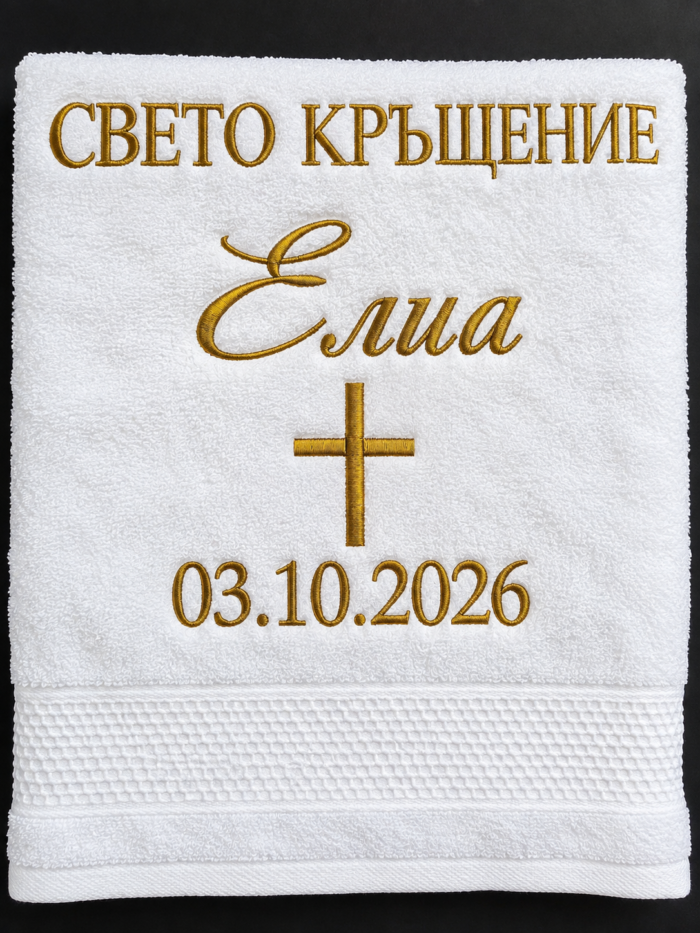 Детайл на златиста бродерия с името Елиа върху бяла хавлия за кръщене